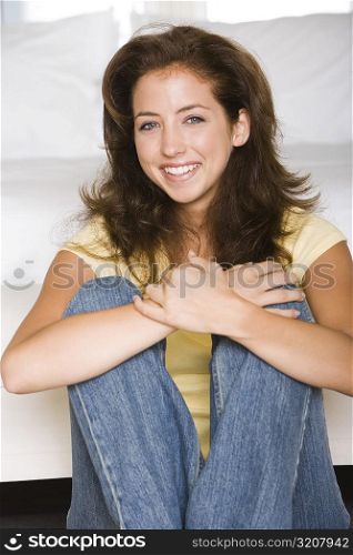 Portrait of a young woman leaning against a bed