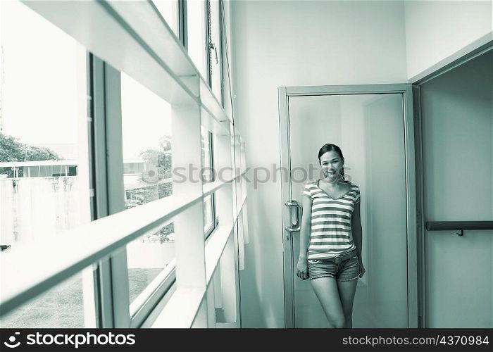Portrait of a young woman leaning against a door and smiling
