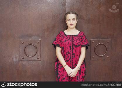 Portrait of a young woman leaning against a metal wall