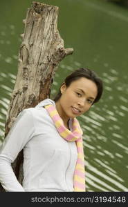 Portrait of a young woman leaning against a tree stump