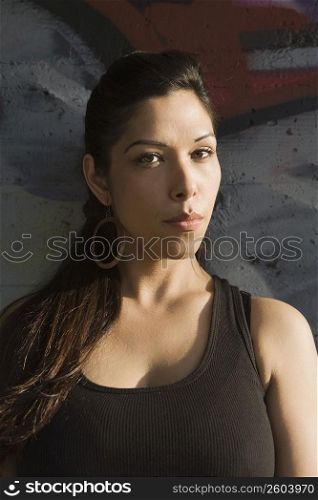 Portrait of a young woman leaning against a wall