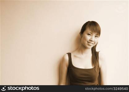 Portrait of a young woman leaning against a wall and smiling