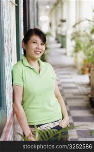 Portrait of a young woman leaning against a wall and smiling