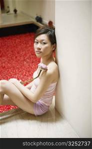 Portrait of a young woman leaning against a wall near a hot tub filled with rose petals