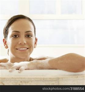 Portrait of a young woman leaning at the edge of a bathtub