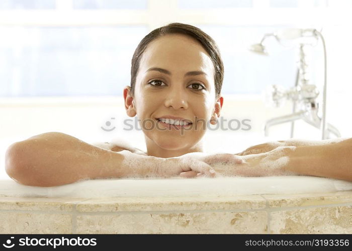 Portrait of a young woman leaning at the edge of a bathtub