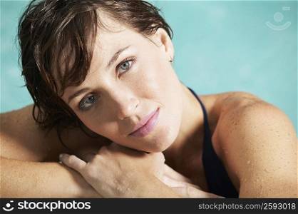 Portrait of a young woman leaning at the edge of a swimming pool