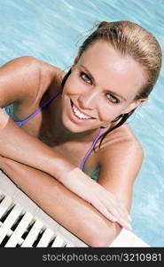 Portrait of a young woman leaning at the edge of a swimming pool