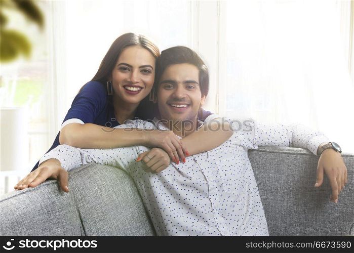 Portrait of a young woman leaning over a young man from behind