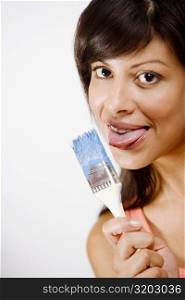 Portrait of a young woman licking a paintbrush