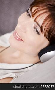 Portrait of a young woman listening music with headphones