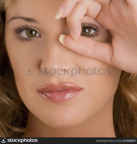 Portrait of a young woman looking through a circle formed by her fingers