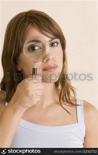 Portrait of a young woman looking through a magnifying glass