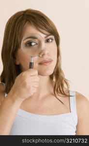 Portrait of a young woman looking through a magnifying glass