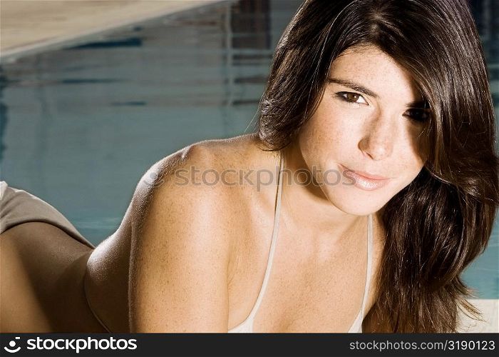 Portrait of a young woman lying at the poolside