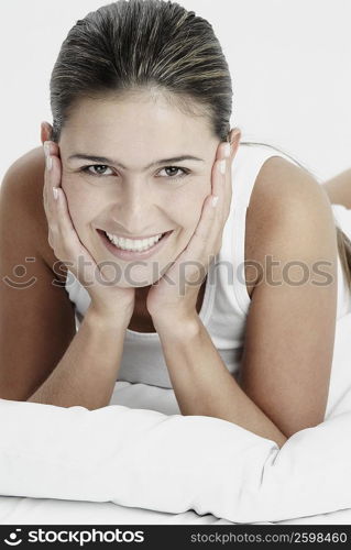 Portrait of a young woman lying down with her hands on her chin