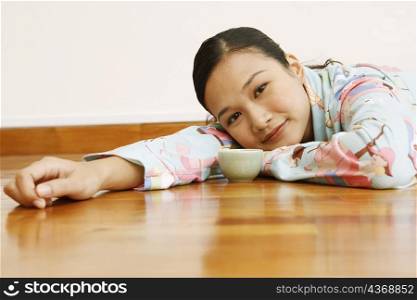 Portrait of a young woman lying in front of a tea cup