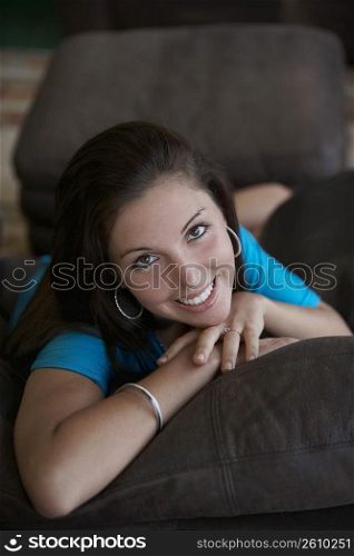 Portrait of a young woman lying on a couch and smiling