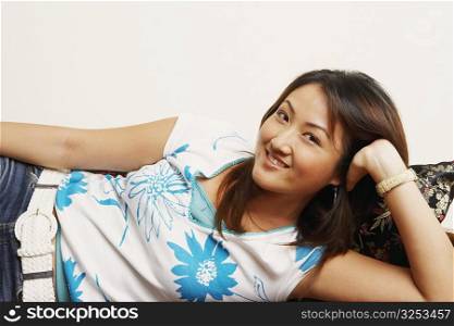 Portrait of a young woman lying on a couch and smiling