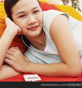Portrait of a young woman lying on the bed and listening to music on headphones