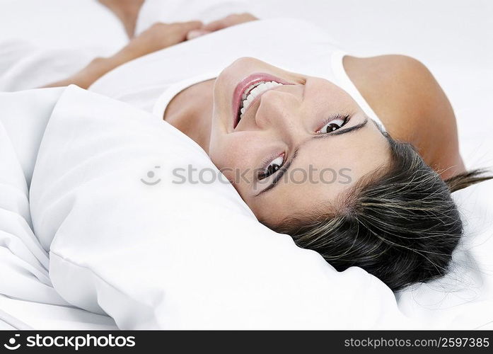 Portrait of a young woman lying on the bed and smiling