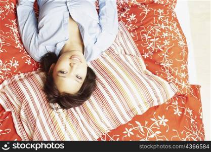 Portrait of a young woman lying on the bed smiling