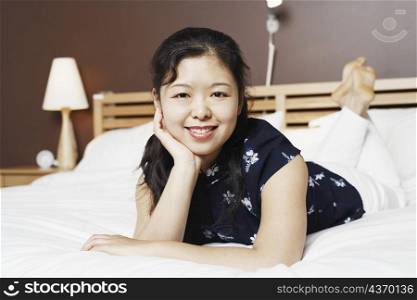 Portrait of a young woman lying on the bed thinking with her hand on her chin