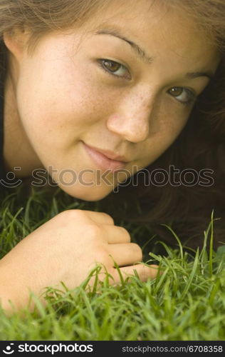 Portrait of a young woman lying on the grass