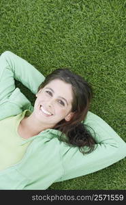 Portrait of a young woman lying on the grass and smiling