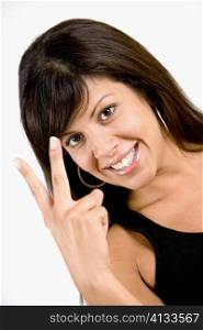 Portrait of a young woman making a peace sign and smiling