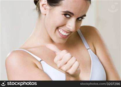 Portrait of a young woman making a thumbs up sign