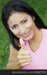 Portrait of a young woman making a thumbs up sign and smiling