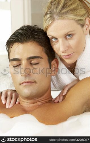 Portrait of a young woman massaging a young man in a bubble bath
