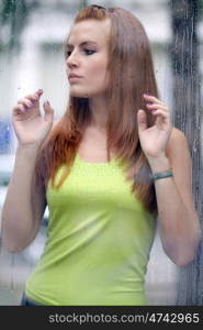 Portrait of a young woman near the window after the rain