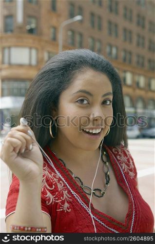 Portrait of a young woman offering an ear bud to listen music