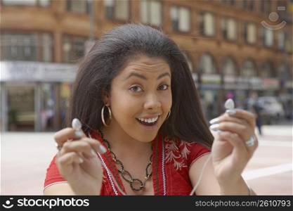 Portrait of a young woman offering an ear bud to listen music