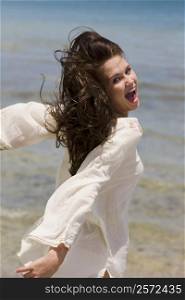 Portrait of a young woman on the beach with her arms outstretched