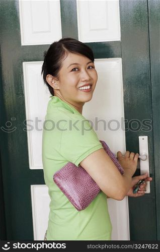 Portrait of a young woman opening a door