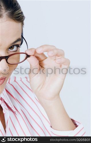 Portrait of a young woman peeking over her eyeglasses