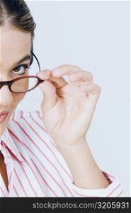 Portrait of a young woman peeking over her eyeglasses