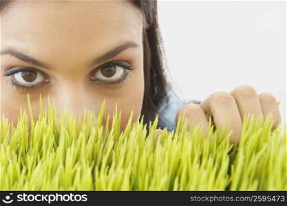 Portrait of a young woman peeking over wheatgrass