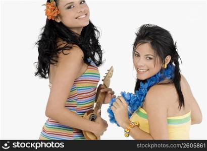 Portrait of a young woman playing a ukulele and a teenage girl dancing