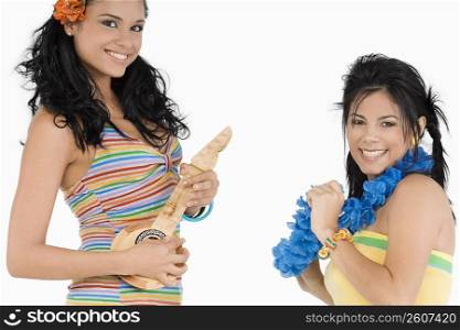 Portrait of a young woman playing a ukulele and a teenage girl snapping