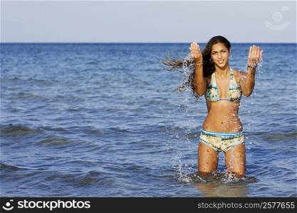 Portrait of a young woman playing with water in the sea