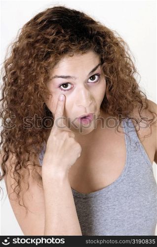 Portrait of a young woman pointing at her eye