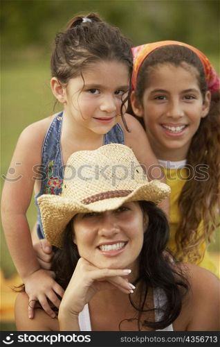 Portrait of a young woman posing with her two daughters with her hand on her chin