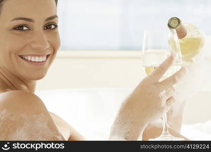 Portrait of a young woman pouring white wine into a wineglass