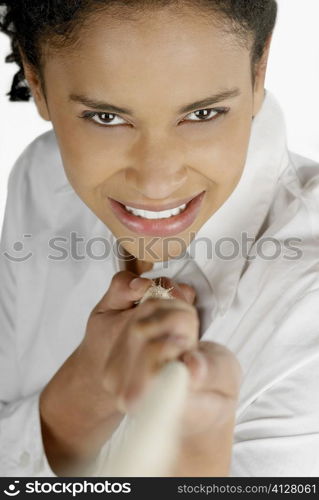 Portrait of a young woman pulling a rope and smiling