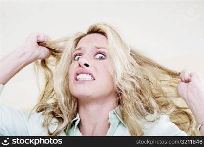 Portrait of a young woman pulling her hair and clenching her teeth