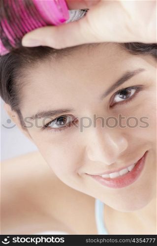 Portrait of a young woman putting curlers in her hair
